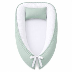 plain green baby nest with padded raised sides and a small matching head pillow, designed to create a cozy, secure sleeping space for infants.
