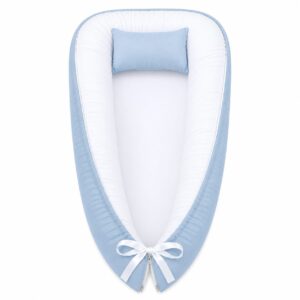 Blue outside and white inside baby nest with padded raised sides and a small matching head pillow, designed to create a cozy, secure sleeping space for infants.