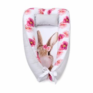 Bubblegum Bunny baby nest with padded raised sides and a small matching head pillow, designed to create a cozy, secure sleeping space for infants.