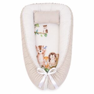 Beige Woodlands Leaf and Tree baby nest with padded raised sides and a small matching head pillow, designed to create a cozy, secure sleeping space for infants.