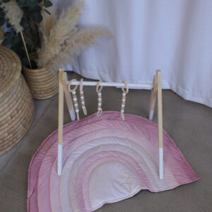 Pink rainbow-shaped baby playmat with ombré shades, perfect for nursery décor and play, by Cinnamon and Spice Baby Boutique.