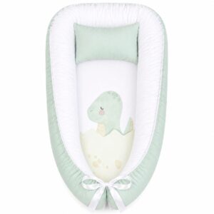 Green Dino Dinosaur Hatching Love baby nest with padded raised sides and a small matching head pillow, designed to create a cozy, secure sleeping space for infants.