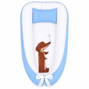 Blue Dachshund Party Adventures baby nest with padded raised sides and a small matching head pillow, designed to create a cozy, secure sleeping space for infants.